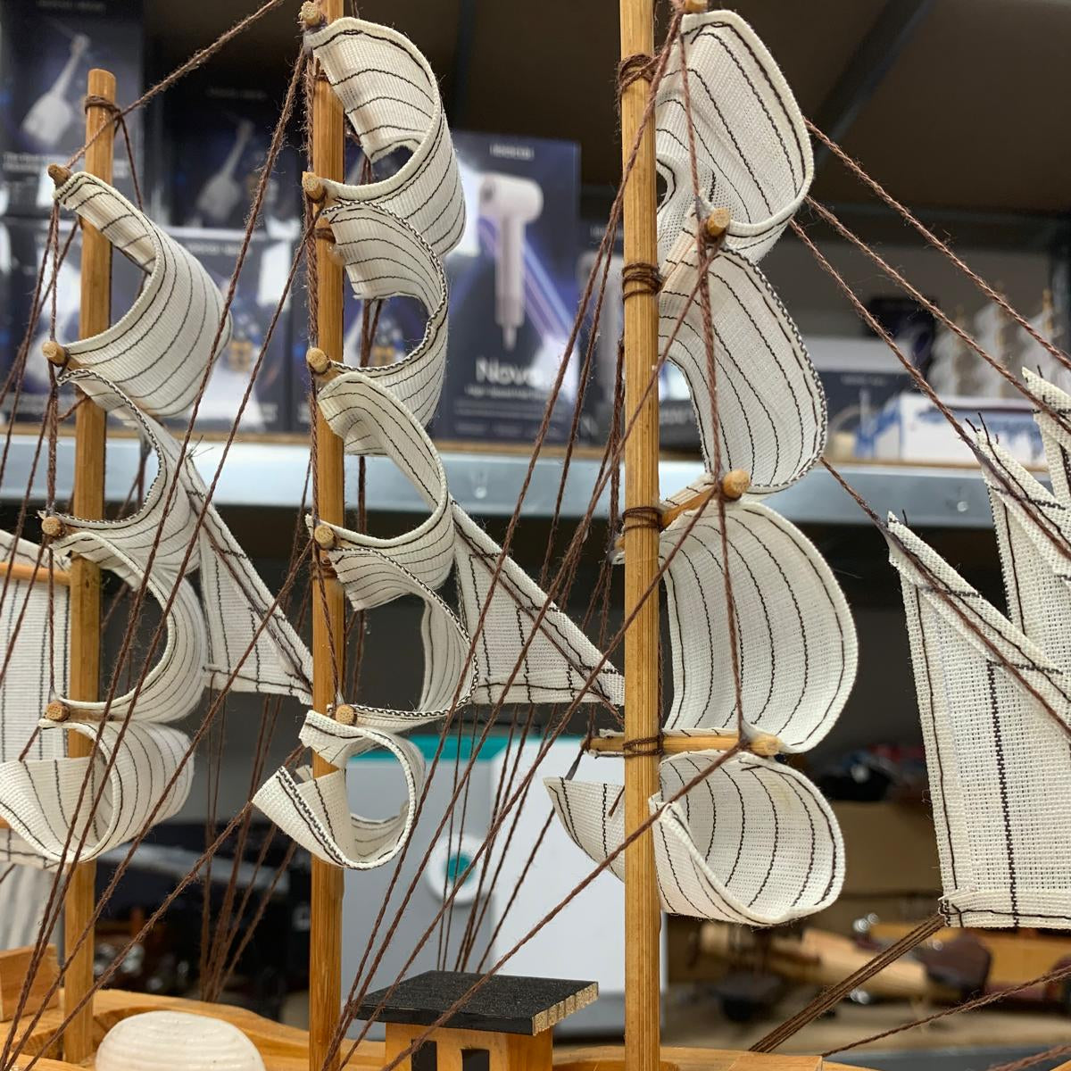 Wooden model ship with multiple sails on a blurred background