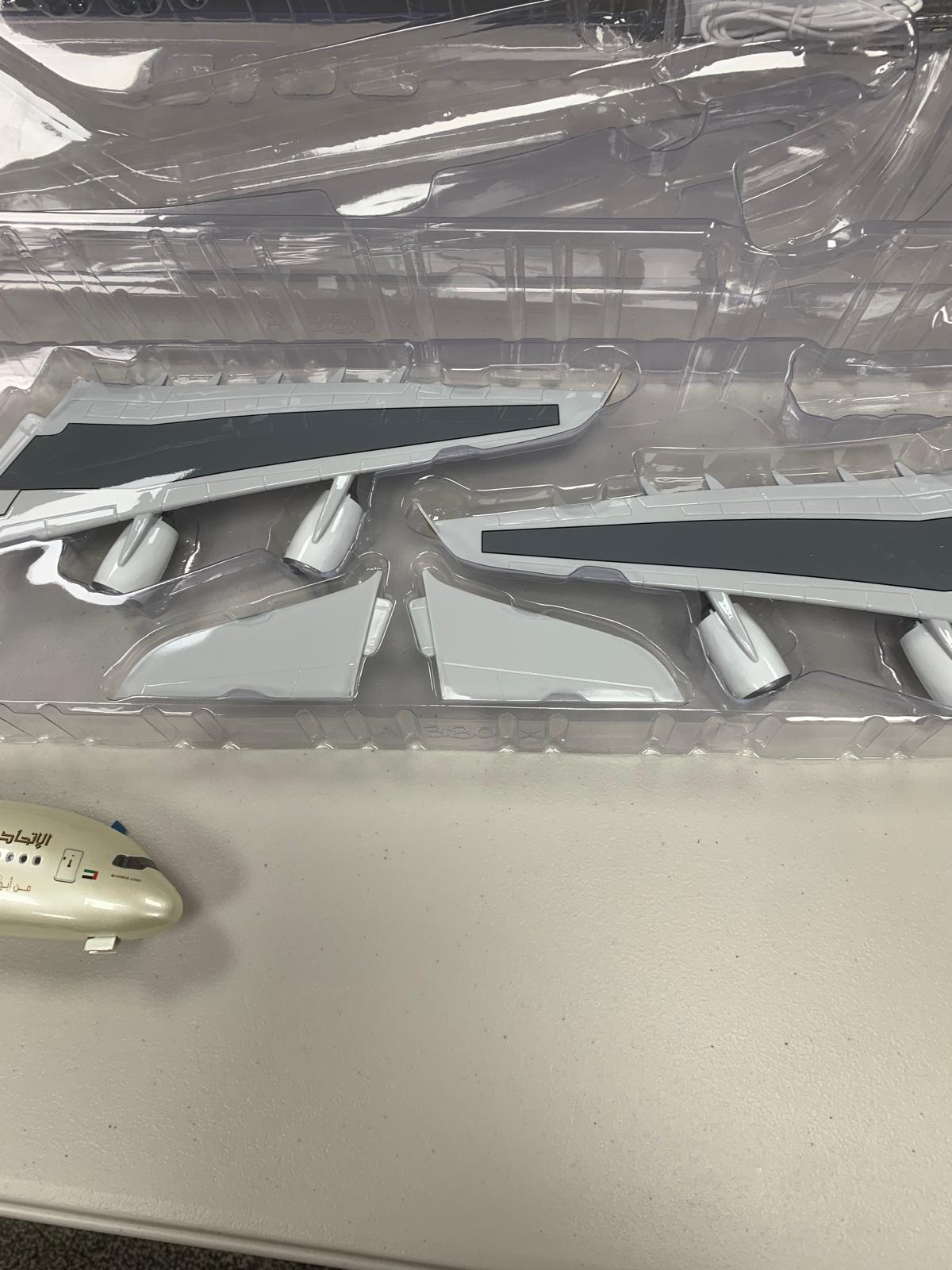 Model ethiad model plane body parts in a clear plastic case on a white surface