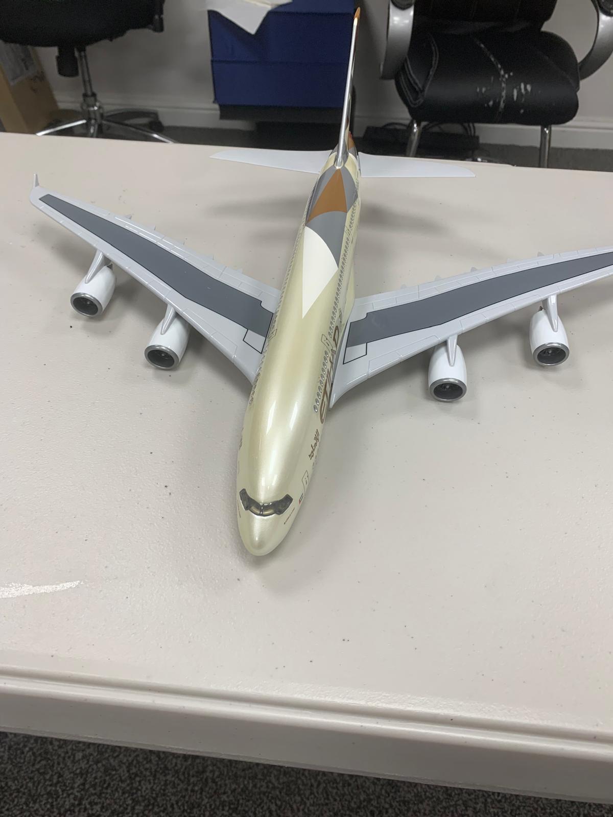 Model airplane on a white surface with chairs in the background