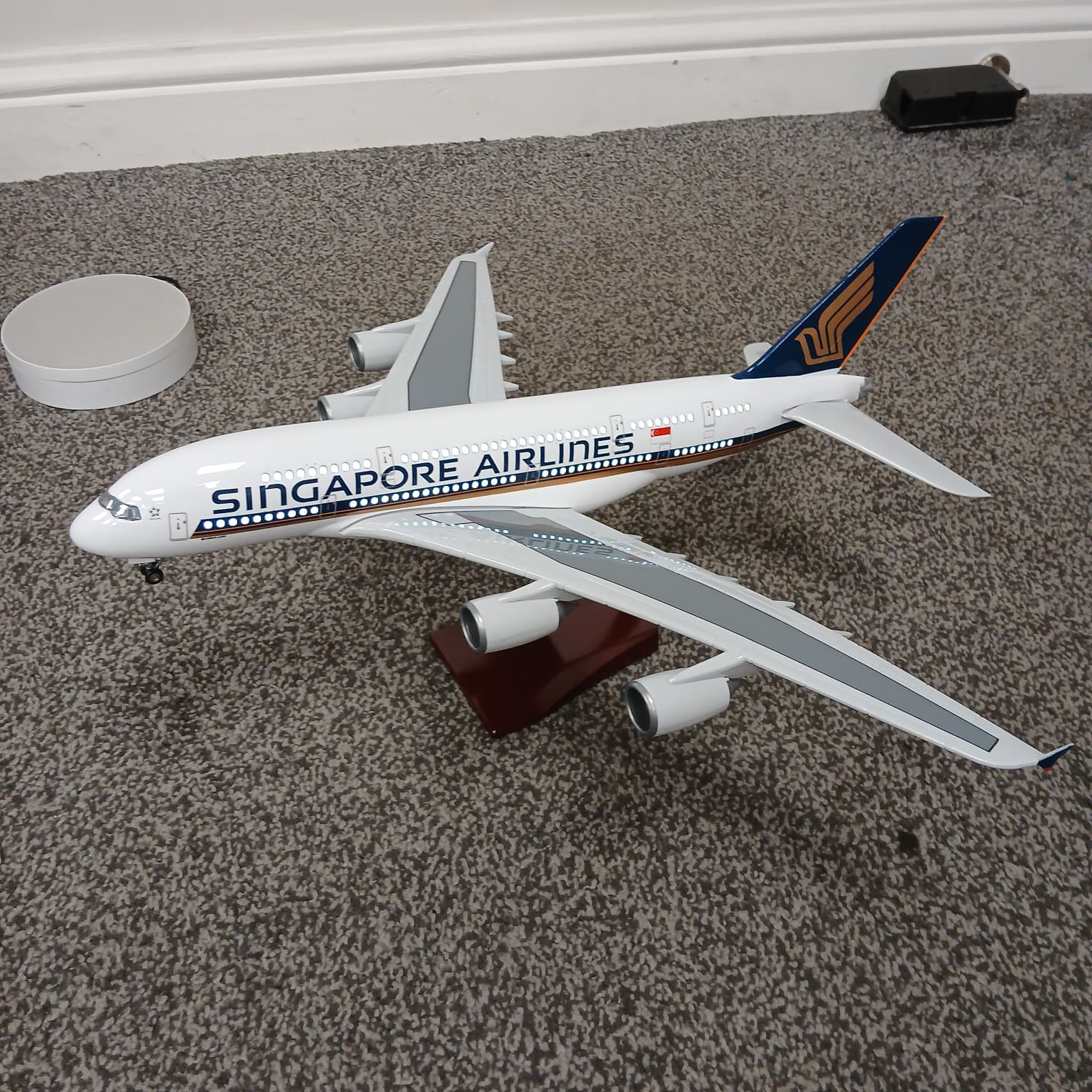 Model of a A380 Singapore Airlines airplane on a carpeted floor with lights on